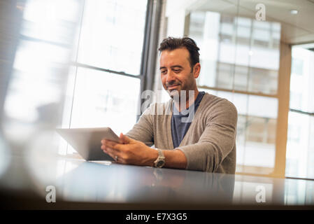 La vie de bureau. Un homme assis à un bureau à l'aide d'une tablette numérique. Banque D'Images