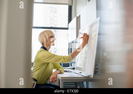 La planification d'une femme à l'aide d'un tableau mural et post it. Banque D'Images