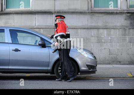 Un gardien de la circulation (agent d'exécution civile) en patrouille l'émission des contraventions de stationnement de voitures stationnées illégalement à Cardiff au Pays de Galles. Banque D'Images