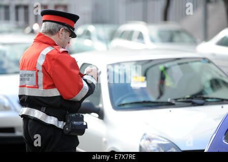 Un gardien de la circulation (agent d'exécution civile) en patrouille l'émission des contraventions de stationnement de voitures stationnées illégalement à Cardiff au Pays de Galles. Banque D'Images