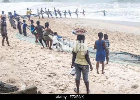 Les gens dans une ligne à pêche tirant de l'océan Banque D'Images