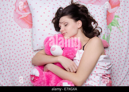 Young Beautiful woman sleeping in bed with teddy bear Banque D'Images