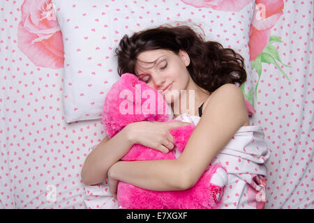 Young Beautiful woman sleeping in bed with teddy bear Banque D'Images