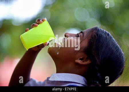 Fille de l'école indienne de l'eau potable à partir d'un verre en plastique Banque D'Images
