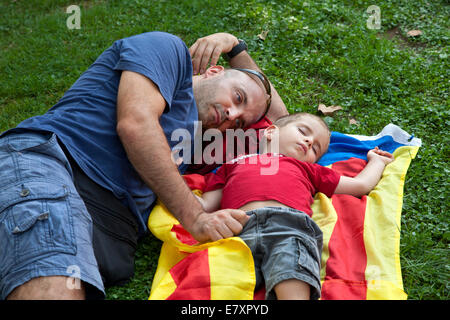 Une indépendance pro homme catalan se trouve à côté de son jeune fils qui s'endort sur le drapeau indépendantiste catalan, Barcelone, Espagne. Banque D'Images