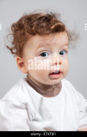 Studio Portrait of a happy 8 mois bébé garçon avec les cheveux bouclés. Banque D'Images