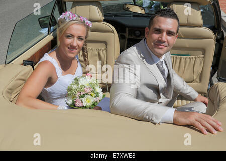 Bride and Groom posing sur le siège arrière d'une voiture ouverte, convertible Banque D'Images