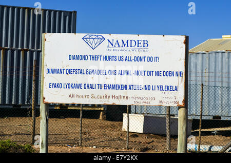 NAMDEB diamond mining company panneau d'avertissement contre le vol de diamants et les conteneurs à l'arrière-plan, Lüderitz, Namibie Banque D'Images