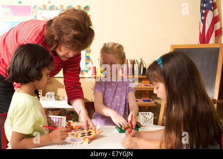 La diversité raciale multi multi ethniques raciales diversifiées multi culturel multiculturel aide à l'enseignant de maternelle trois enfants filles travailler ensemble Banque D'Images