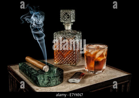 Fumer un cigare s'assoit à côté d'une carafe en cristal de l'alcool. Banque D'Images