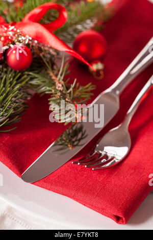 Thème de Noël rouge place avec une serviette rouge sur les plaques blanches décorées de petites boules de Noël rouge et brûlant Banque D'Images