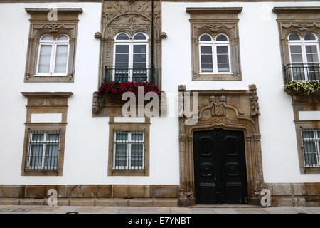 Ornée porte en pierre sculptée et fenêtres de la façade du manoir Casa de Carreira avec géraniums dans la boîte de fenêtre, Viana do Castelo , nord du Portugal Banque D'Images