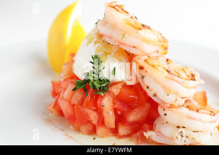 Crevettes frais et savoureux avec le citron et les tomates sur le plat blanc Banque D'Images