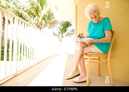 Vieille Femme assis sur une chaise et de mots croisés Banque D'Images