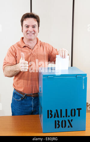 Homme de race blanche au milieu des électeurs adultes laissant tomber son bulletin dans la boîte et en donnant un coup de pouce. Banque D'Images