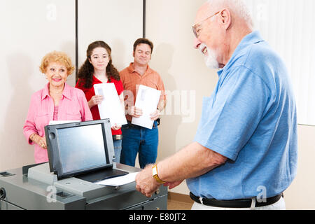 Hauts homme sourit comme il jette son bulletin sur une nouvelle machine de vote électronique. Banque D'Images