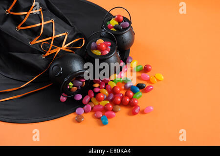 Happy Halloween Candy dans trick or treat transporter avec des chaudrons de sorcières hat sur fond orange. Banque D'Images