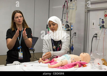 Calgary, Alberta, Canada, 27 sept., 2014. Infirmière en soins intensifs pédiatriques Helen Catene (à gauche) et enfants médecin Amani Azizalrahman la démonstration de l'utilisation d'un système informatisé de mannequin pédiatrique dans le nouveau KidSIM Centre à l'Hôpital pour enfants de l'Alberta pendant les Portes Ouvertes YYC. L'installation d'avant-garde, le plus grand centre de simulation pédiatrique au Canada, fournit aux praticiens et aux familles de patients atteints d'une expérience clinique simulée aussi près que possible des situations de vie. Banque D'Images