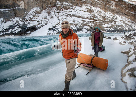 Deux porteurs sont tirant des trekkers assurance sur la rivière Zanskar trek Chadar pendant Banque D'Images