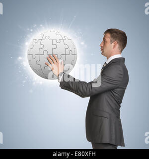 Man in suit tenir puzzle sphere Banque D'Images