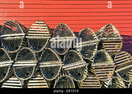 Casiers à homard empilés contre un abri de pêche rouge à Terre-Neuve, Canada Banque D'Images