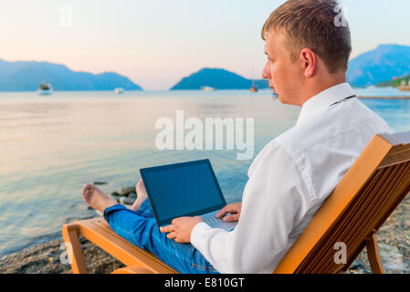 Homme de vêtements de bureau travaillant sur la plage Banque D'Images