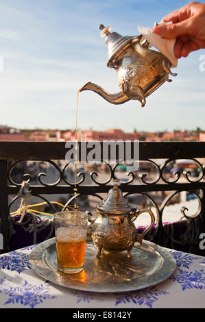 Close up vertical de thé à la menthe traditionnel versé depuis une hauteur dans de petits verres donnant sur la place Jemaa el-Fna à Marrakech Banque D'Images