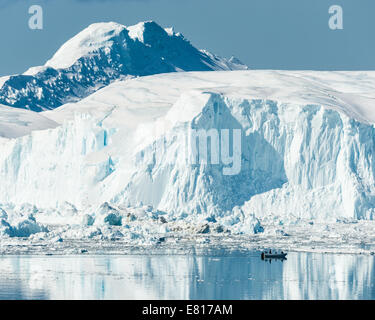 Bateau à moteur éclipsé par de majestueuses glacier sur mer calme. Banque D'Images