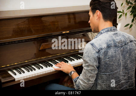 Beau mâle jeune artiste jouant son piano droit classique en bois, portrait Banque D'Images