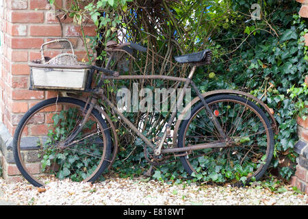 Rusty vintage Bicycle appuyé contre un mur de brique rouge Banque D'Images