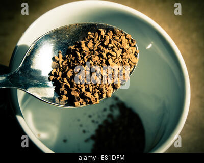 Le café instantané granules sur une cuillère à café, est versé dans une tasse. Banque D'Images