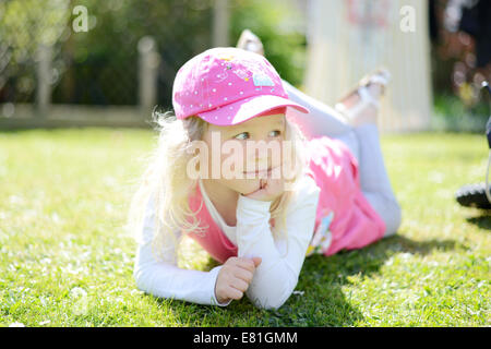 Petite fille de cinq ans posant dans le jardin à l'écart de l'appareil photo Banque D'Images