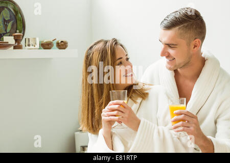 Couple drinking orange juice en peignoirs Banque D'Images