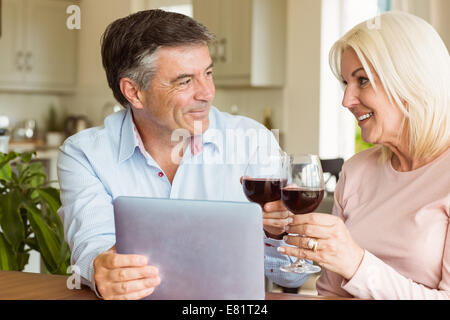 Mature Woman using tablet drinking red wine Banque D'Images