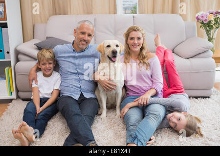 Les parents et les enfants sur un tapis avec le labrador Banque D'Images