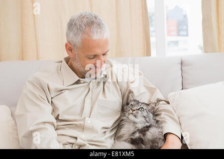 Homme heureux avec son chat sur canapé Banque D'Images