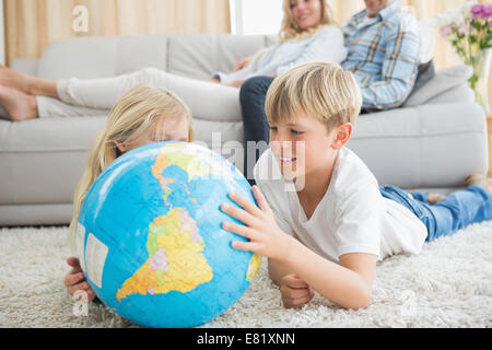 Frères et sœurs looking at globe sur le plancher Banque D'Images