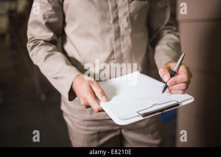 Mid section de l'employé de l'entrepôt avec presse-papiers Banque D'Images