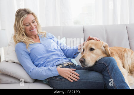 Smiling blonde woman petting son golden retriever Banque D'Images