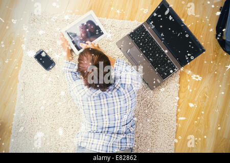 Jeune femme brune allongée sur le sol à l'aide de son ordinateur portable et tablette Banque D'Images