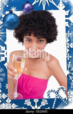 Jeune femme tenant un verre de champagne tout en regardant la caméra Banque D'Images