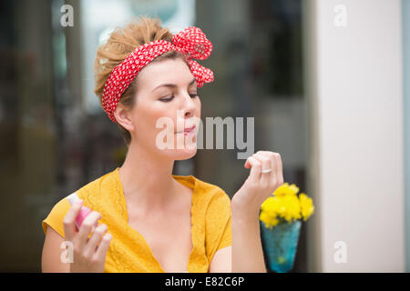 Jolie hipster en soufflant sur ses ongles humides Banque D'Images