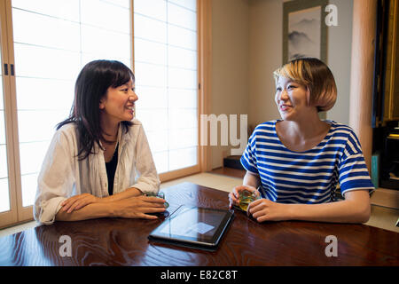 Deux femmes assises à une table avec une tablette numérique. Banque D'Images