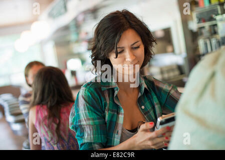 Une femme dans un diner, en regardant son téléphone portable. Banque D'Images