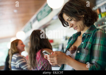 Une femme dans un diner, en regardant son téléphone portable. Banque D'Images