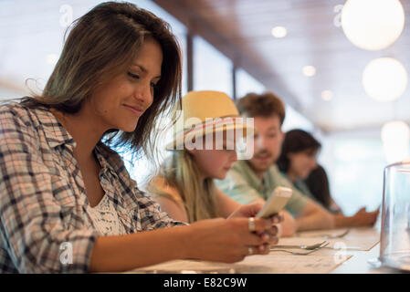 Une femme dans un diner, en regardant son téléphone portable. Banque D'Images