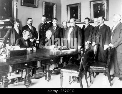 L'ambassadeur français Pierre Paul Cambon la signature du Protocole de paix, comme le Président William McKinley et dix autres hommes watch. 1898 Banque D'Images