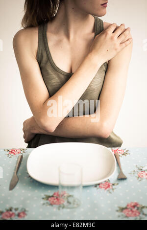 Femme en face d'une assiette vide. Banque D'Images