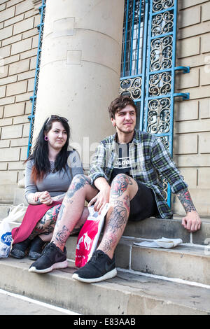 Un jeune couple avec des tatouages s'asseoir sur les marches à l'Hôtel de ville du centre-ville de Sheffield, UK Banque D'Images