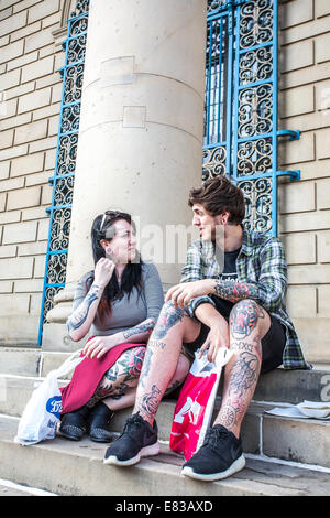 Un jeune couple avec des tatouages s'asseoir sur les marches à l'Hôtel de ville du centre-ville de Sheffield, UK Banque D'Images